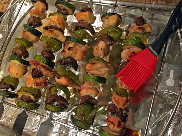 chicken kebabs on kabob skewers and stand with basting brush